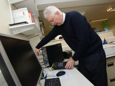 Man PAT testing a computer at a desk